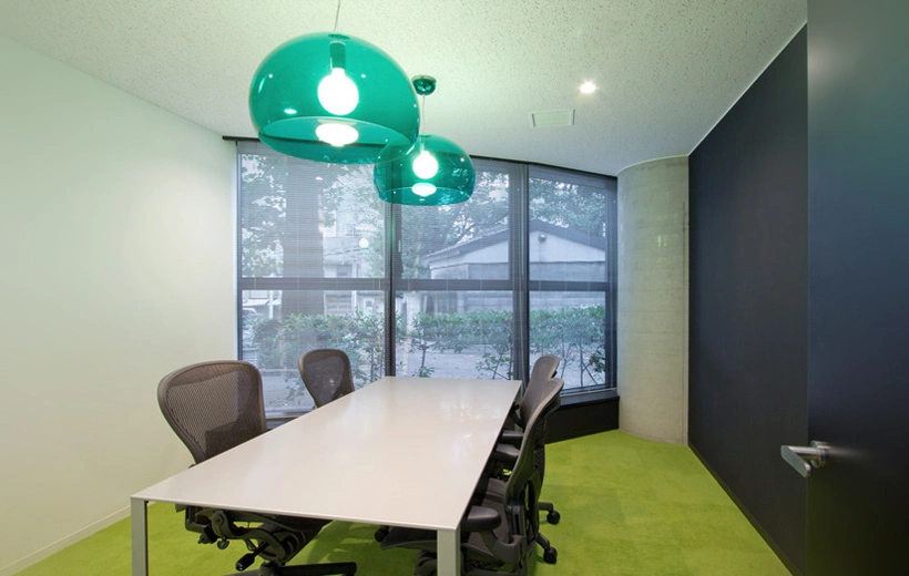 gallery-image-04 feature a distinctive meeting room with green carpet and prominent green pendant lights