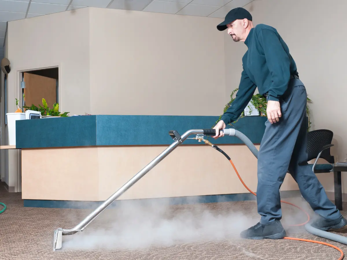 A commercial cleaner vacuums the carpet of a hotel front desk.